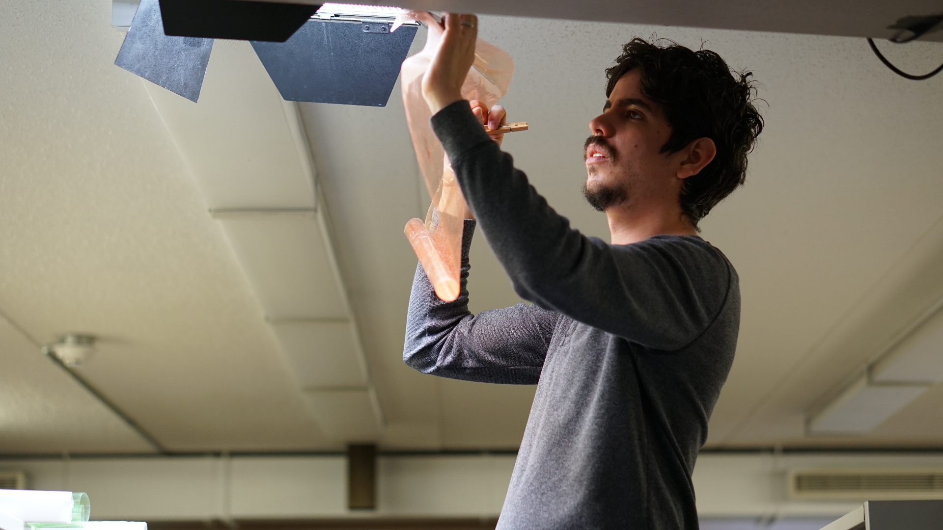Andres clipping a CTO gel to a ceiling light fixture.