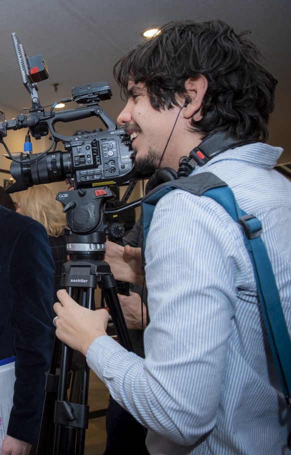 Andres operating a Sony cinema camera on a Sachtler tripod on set.